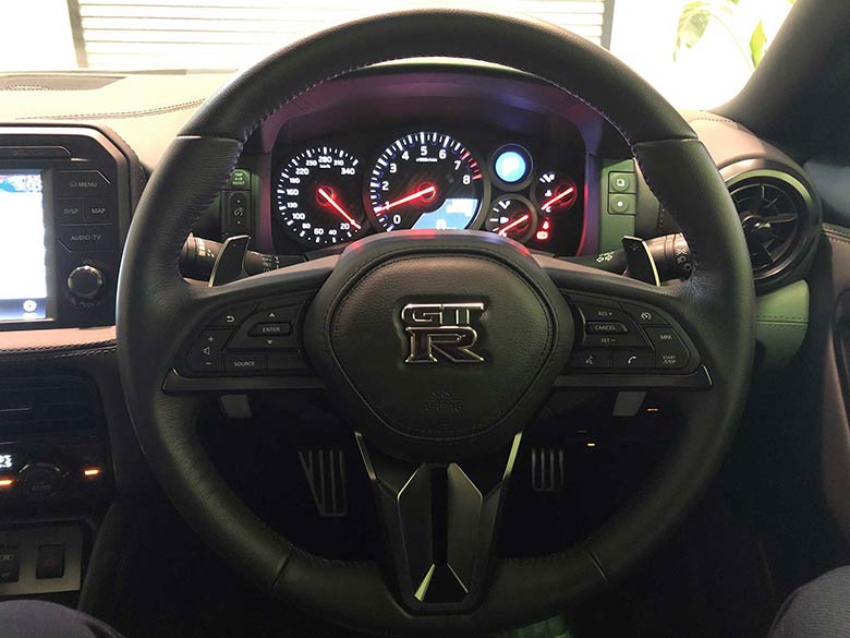 日産 GT-R 3.8 プレミアムエディション 4WD - シルバー 走行17400KM。ステアリングには一体型のパドルシフト、オーディオ操作スイッチ、クルーズコントロールスイッチが装備。 (13/20枚)